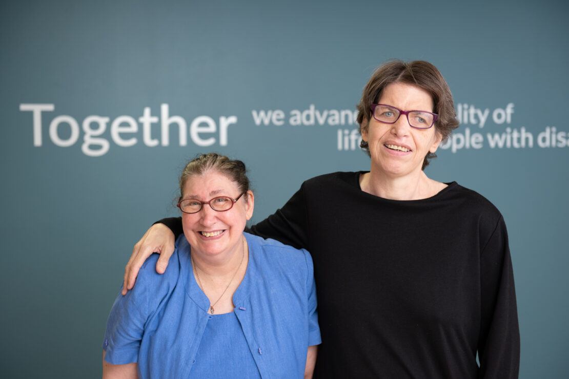 Two women standing in front of company mission statement