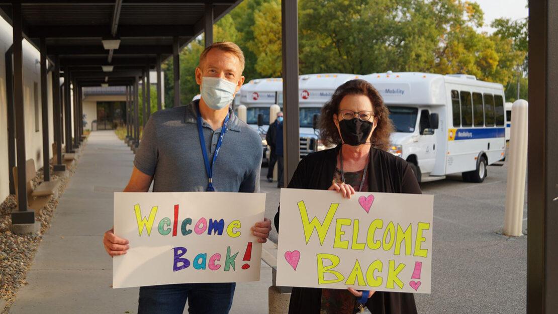 Man and woman wearing masks holding 