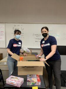 Two women in US Bank shirts with masks on smiling