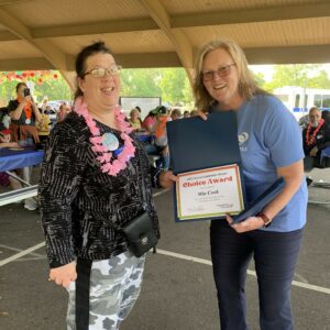 Two women with glasses smiling holding certificate