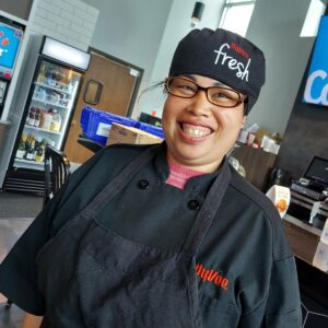 Woman with glasses smiling in a HyVee uniform