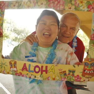 Two people smiling holding an Aloha photo border