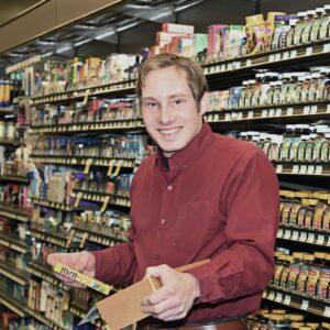 Man in a red shirt standing in a grocery aisle