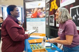 Two women talking at a job fair booth at the University of Minnesota
