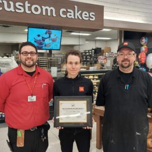 Two men and a woman standing in Cub with an award