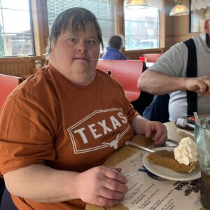 A woman sitting in a restaurant with a slice of pumpkin pie