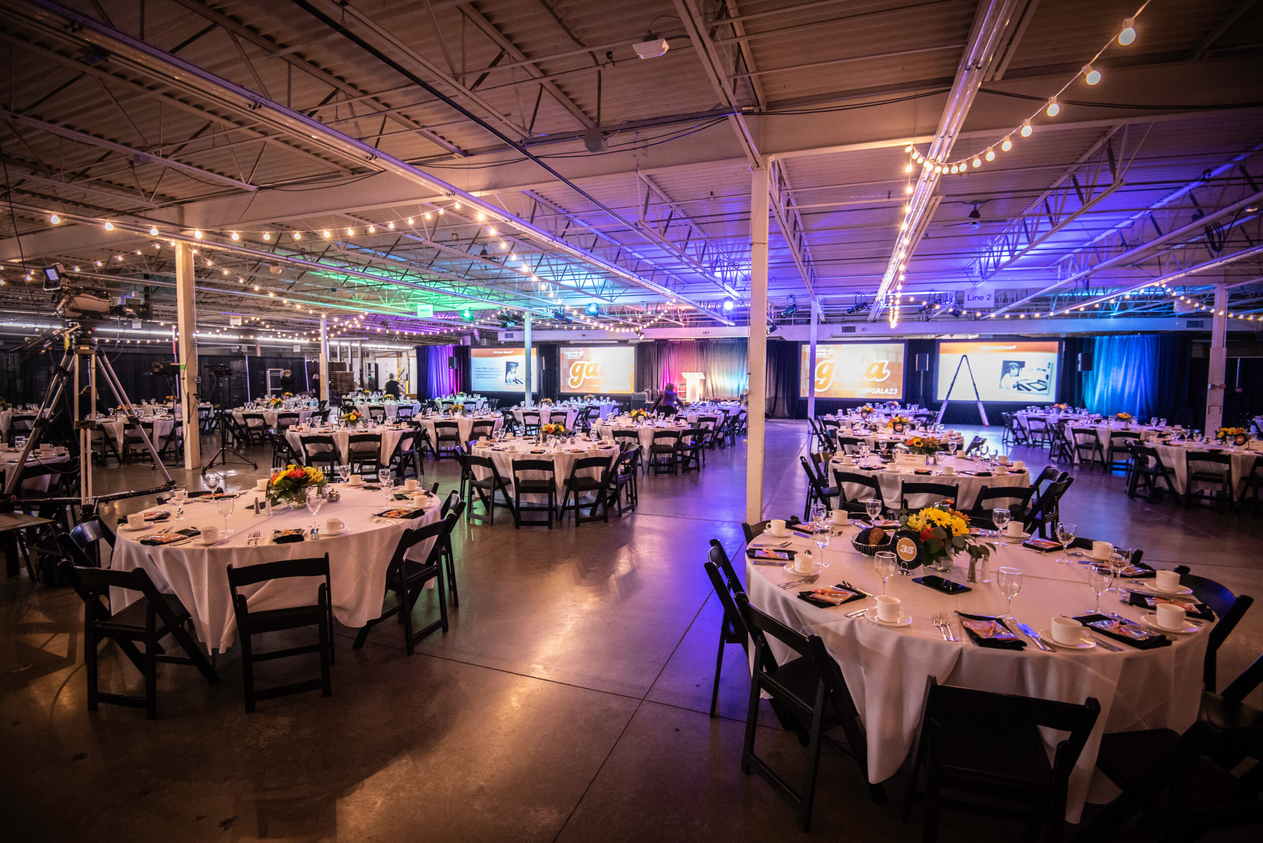 Warehouse with dinner tables and lights for an event