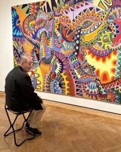Man sitting on a chair admiring a large painting