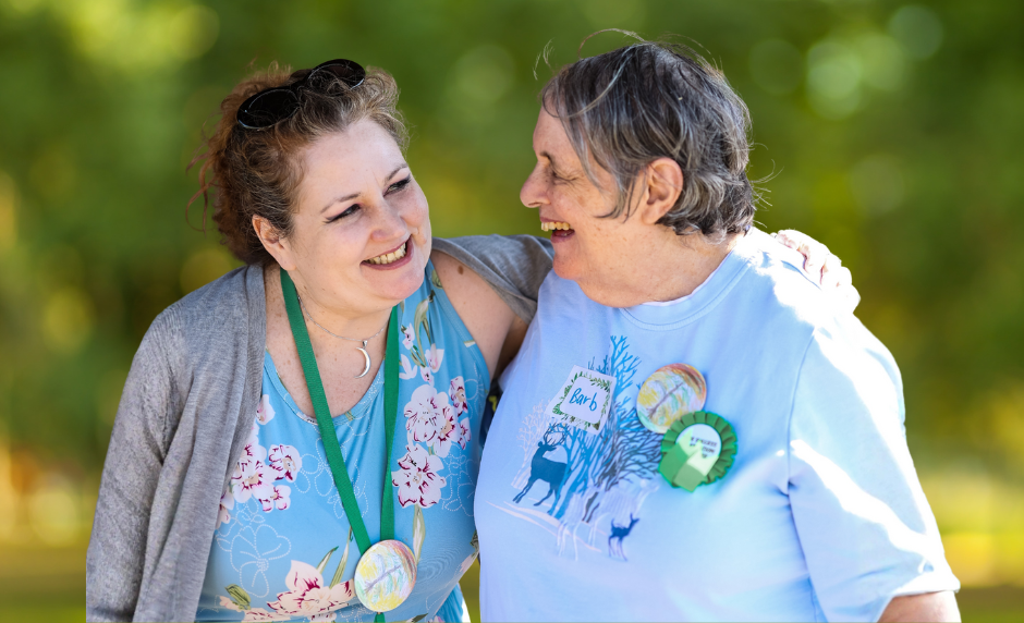 Two people smiling and sharing a joyful moment outdoors